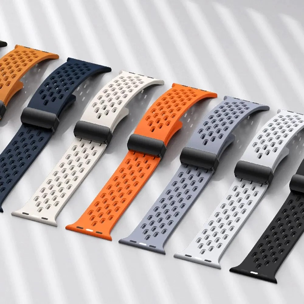 A collection of colorful breathable silicone sport straps for Apple Watch laid out side by side in various colors including navy blue, white, orange, gray, and black, displayed on a light background with soft shadows.