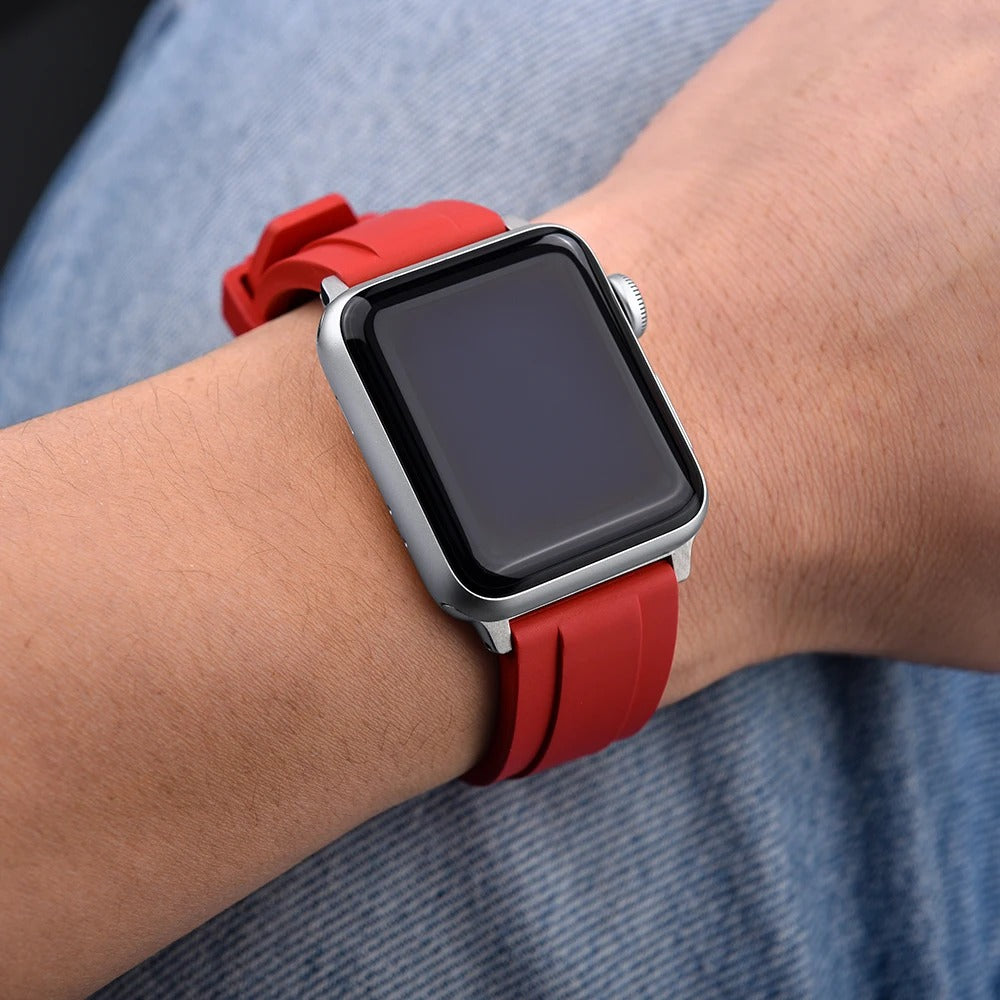Person wearing a smartwatch with a red rubber strap and silver case, screen turned off.